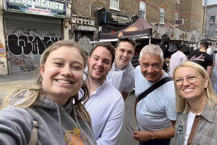 Group of five smiling tourists taking a selfie on a London street during a Jack the Ripper walking tour