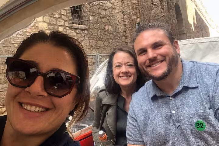 Tour guide standing beside Ape Calessino in a bustling city square, ready for James Bond-themed adventure in iconic locations.