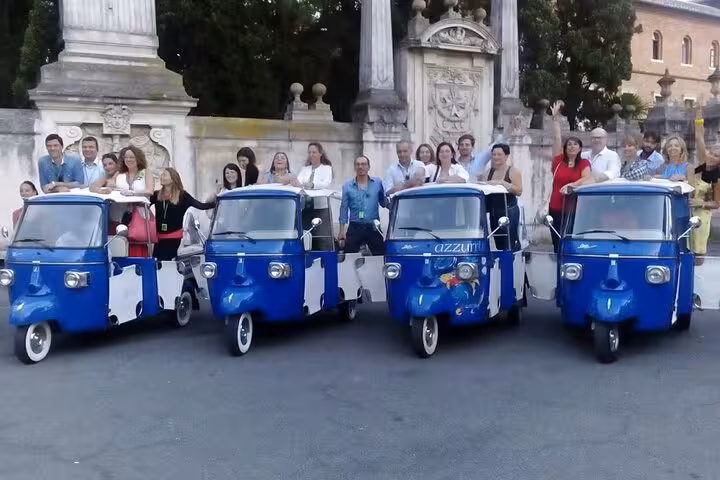 Excited tourists gather by blue Ape Calessino vehicles, ideal for a James Bond-themed sightseeing adventure.