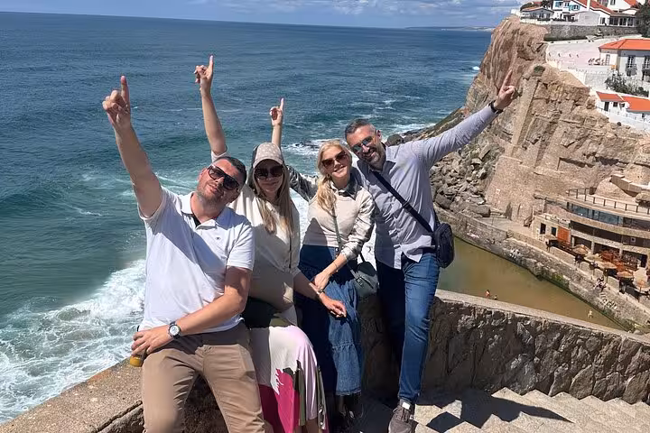 Group of friends posing happily with breathtaking ocean views at Azenhas do Mar during Sintra private tour.