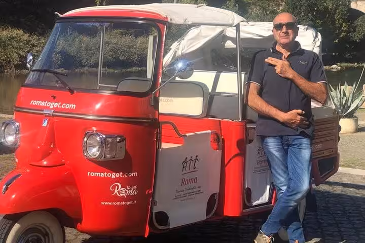 Tour guide poses with a red Ape Calessino, highlighting a unique James Bond tour experience in the city.