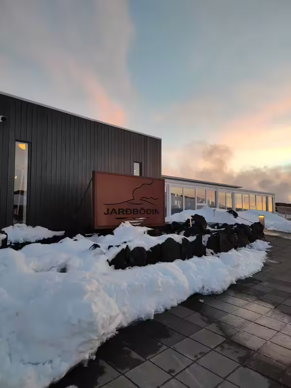 Jardbodin Nature Baths entrance sign covered in snow at sunset near Myvatn Lake, Iceland