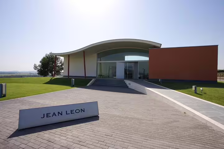 Modern architecture of Jean Leon winery in Penedés under clear skies, highlighting the vineyard's entrance.