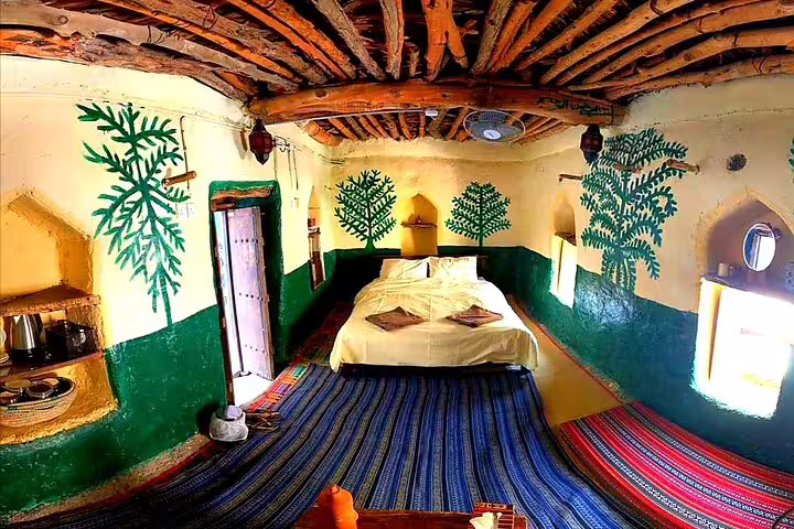 Authentic village bedroom in Jebel Akhdar with hand-painted walls and traditional wooden ceiling design.