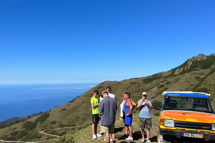 Tourists enjoy a scenic stop on a 4x4 Jeep adventure with panoramic views near Cabo Girão Skywalk, perfect for wine tasting.