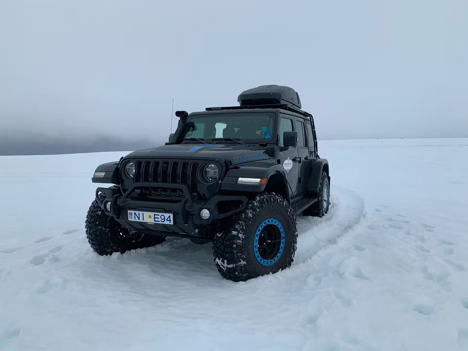 Black Jeep Wrangler Rubicon on Langjokull glacier snowfield in Iceland with blue accents and roof box