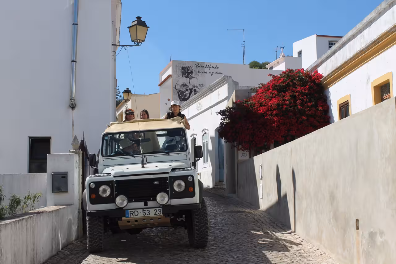 Open-top jeep safari driving through a whitewashed Algarve village on the Benagil cliffs coast tour