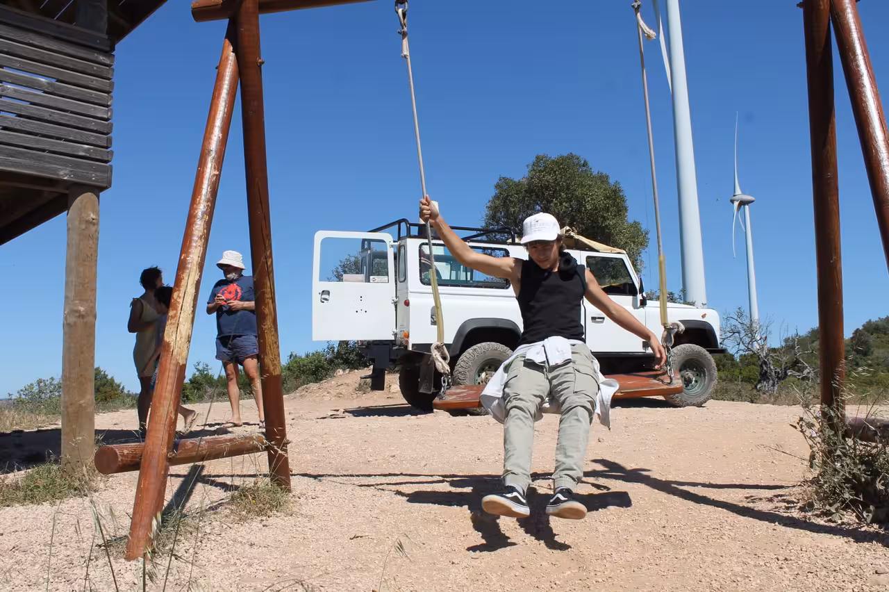 Traveler on rustic swing at scenic viewpoint during Algarve Jeep safari coast tour, en route to Benagil cliffs