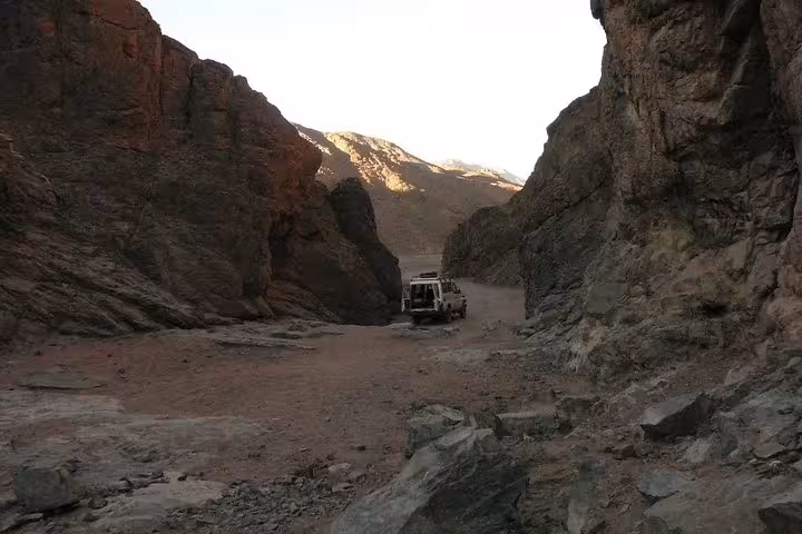 4x4 jeep driving through a rocky canyon on the Mons Claudianus desert safari tour from Safaga, Egypt