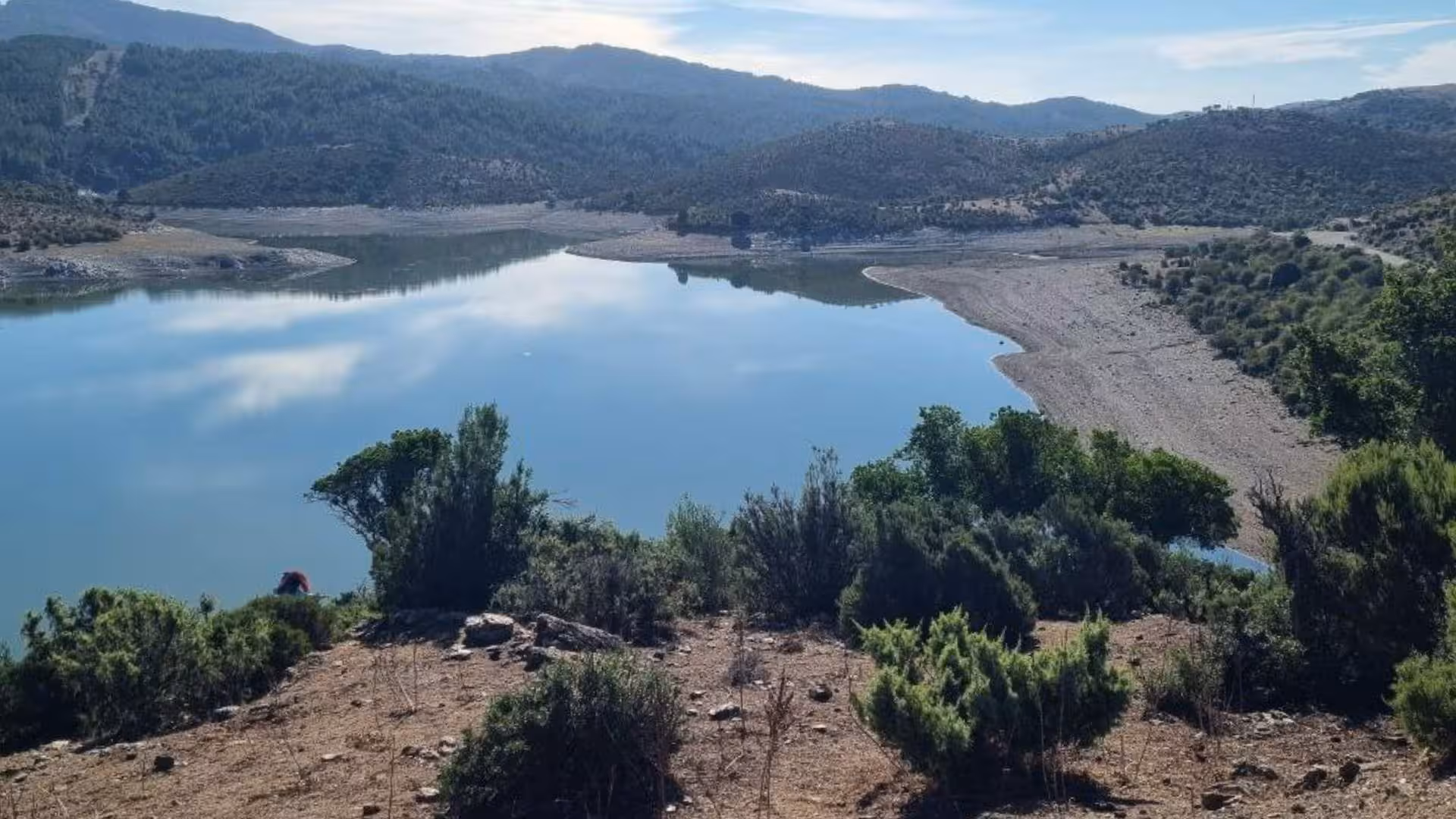 Serene lake surrounded by hills and greenery in Barbagia, ideal spot for a jeep tour from Arbatax.