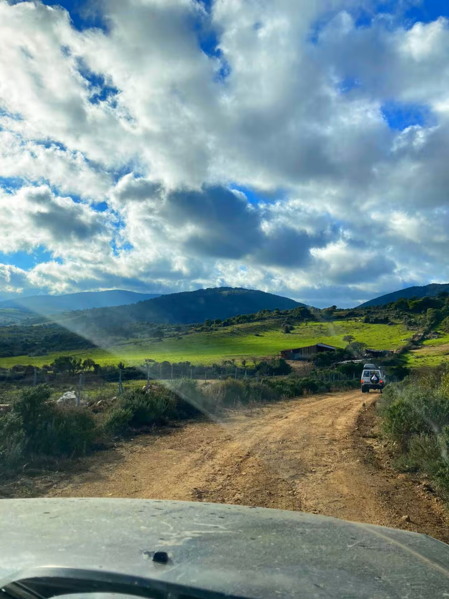 Scenic jeep tour on a rugged dirt road with lush green hills and cloudy skies in Mount Limbara near Tempio.