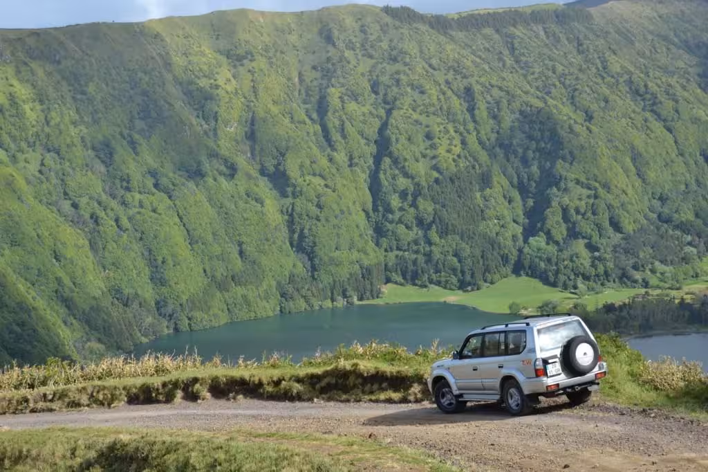 4x4 jeep parked on a dirt track overlooking the green crater walls and twin lakes of Sete Cidades on São Miguel Azores