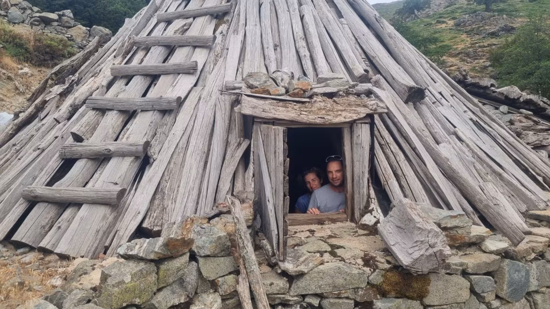 Visitors peeking from a traditional shepherd's hut made of wood and stones in Barbagia, Sardinia.