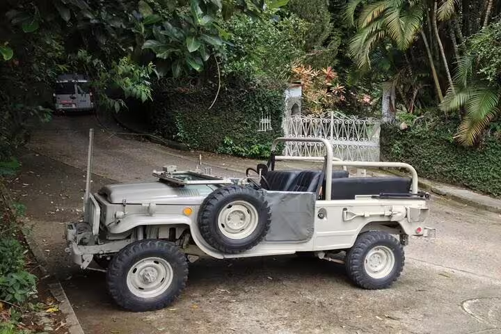 A classic jeep in a leafy driveway, ready for an exciting half-day tour through Rio's Tijuca Rainforest's scenic routes.