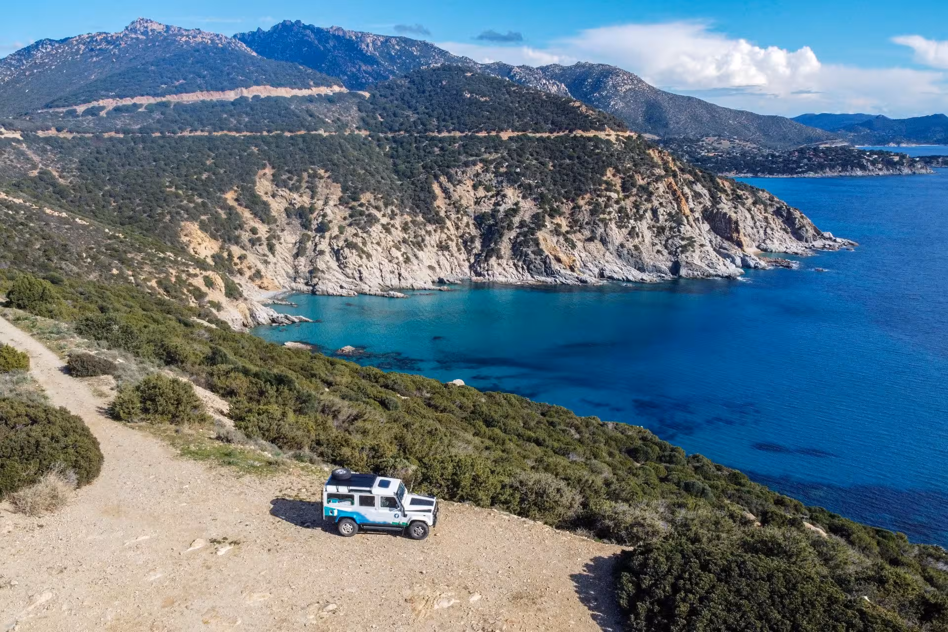 Jeep overlooking the stunning rocky coastline and turquoise waters in Villasimius, Sardinia.