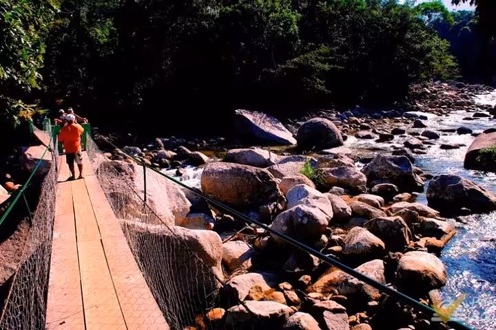 Scenic bridge over rocky stream on Jeep Tour to waterfalls, surrounded by lush greenery and nature.