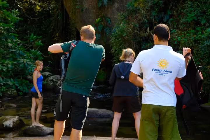 Group of tourists exploring a serene forest waterfall on an exciting Jeep tour experience.