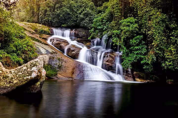 Breathtaking waterfall cascading into a serene pool, surrounded by dense forest on a Jeep tour adventure.