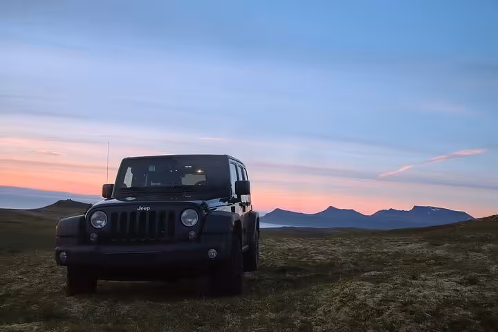 Black Jeep Wrangler parked on Snaefellsnes Peninsula at sunset with mountains in background
