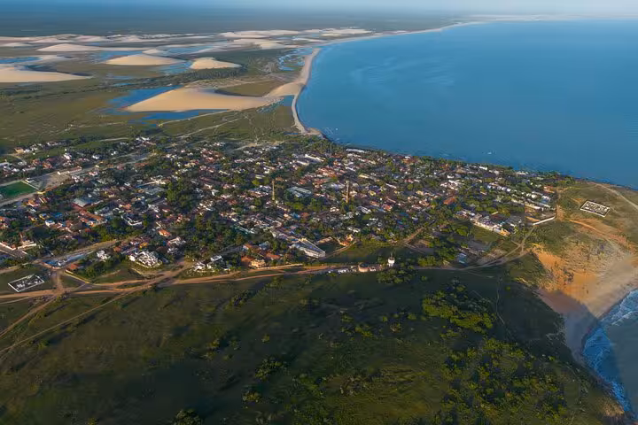 Aerial view of Jericoacoara coastal town with dunes and ocean highlighting scenic airport transfer route