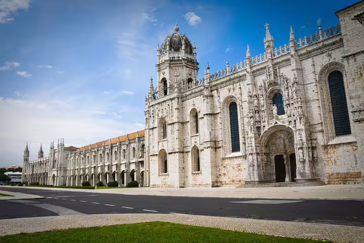 Majestic Jerónimos Monastery in Lisbon under a clear blue sky, showcasing stunning Manueline architecture and rich history.
