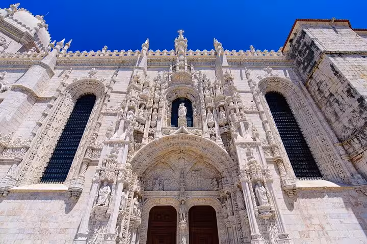 Stunning view of Jerónimos Monastery's intricate Manueline architecture under a clear blue Lisbon sky.