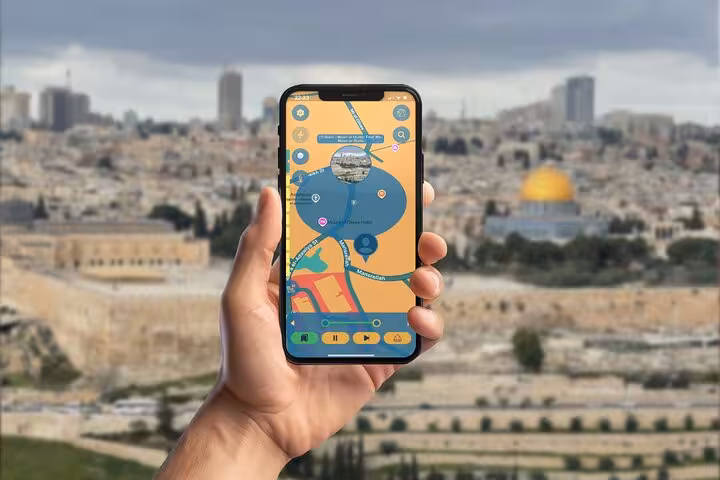 Hand holding smartphone with interactive map app showing Jerusalem Old City with Dome of the Rock in background