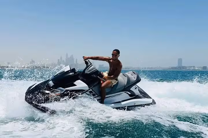 Rider speeding on jet ski with Dubai skyline in background, guided jet ski adventure 30-min or 1-hour