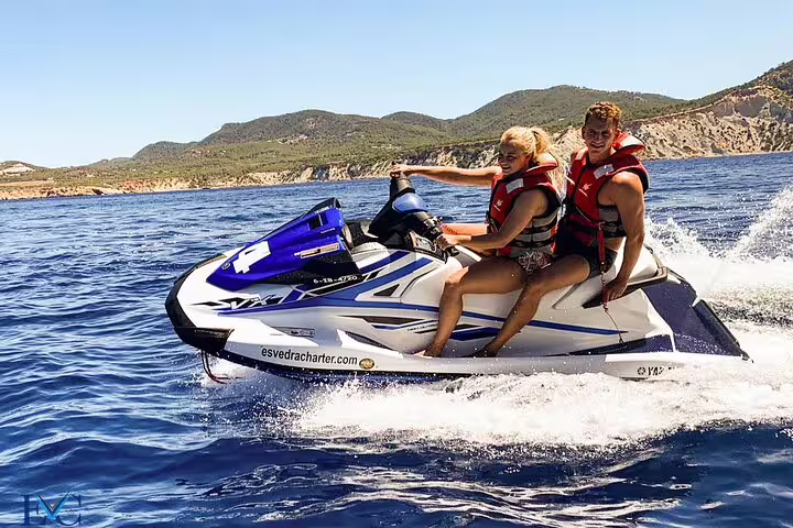 Two riders on a jet ski speeding on the Portitxol tour, Ibiza coastal excursion with sea spray and views