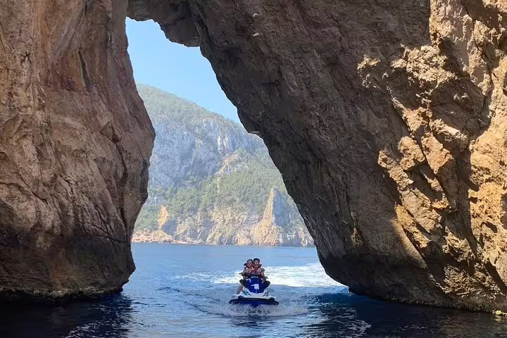 Jet ski entering a sea cave arch on the Portitxol excursion, Ibiza adventure tour with dramatic cliffs