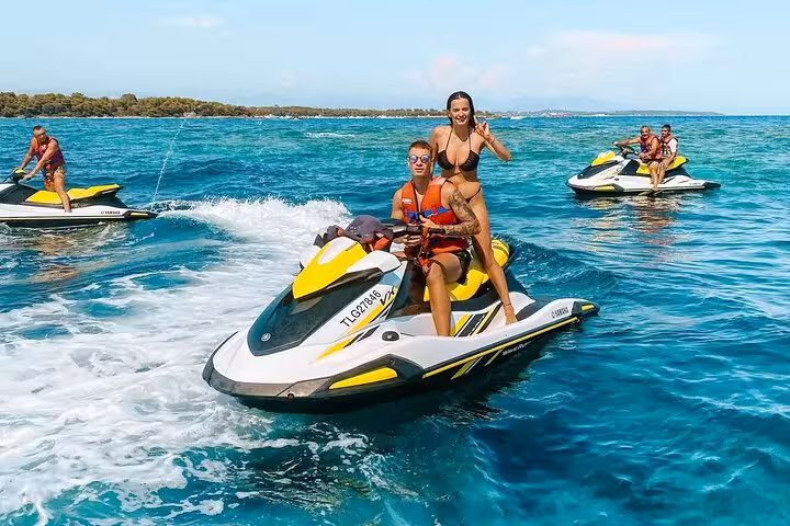 Couple riding a yellow Yamaha jet ski on turquoise waters near Antibes with other jet skis in background