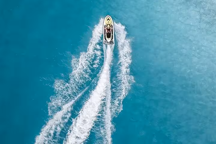 Aerial view of a jet ski speeding across turquoise waters of the French Riviera, leaving a white wake trail