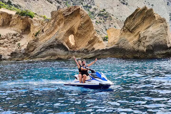 Couple on jet ski at Atlantis Ibiza near San Antonio, posing on calm sea with iconic rock arch backdrop