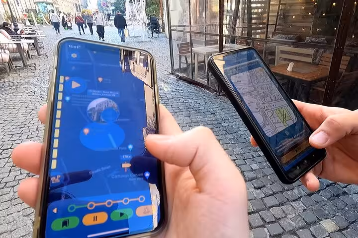 Two smartphones displaying the Jewish Bucharest GPS walking tour app on historic cobblestone streets