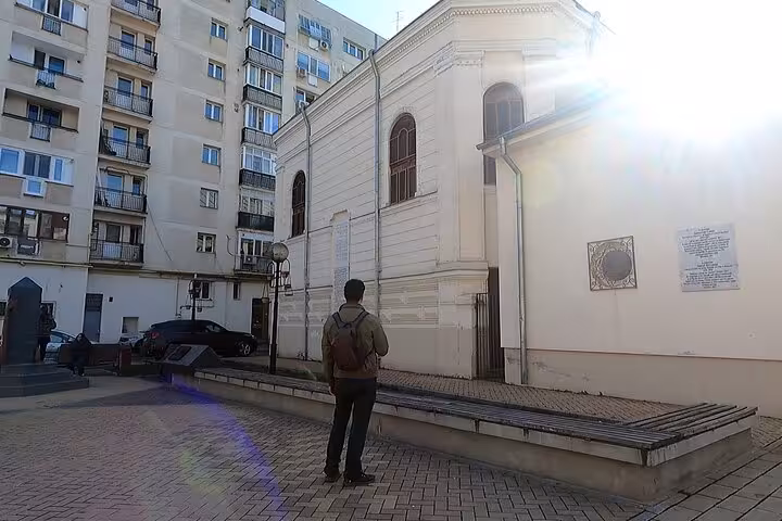 GPS walking tour app on smartphone held near a Jewish memorial monument with Star of David in Bucharest