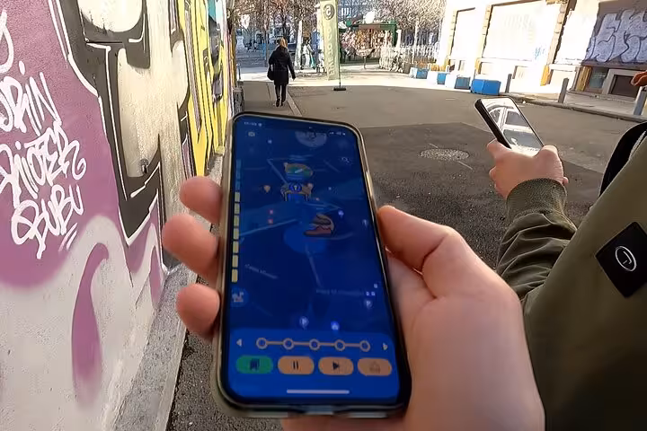 Traveler holding GPS tour app phone navigating Jewish Bucharest self-guided walking tour near graffiti wall