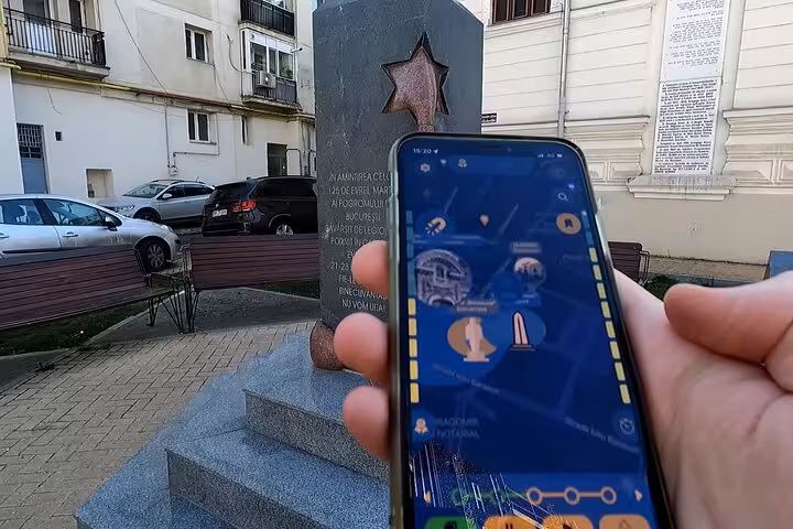 GPS walking tour app on smartphone held near a Jewish memorial monument with Star of David in Bucharest