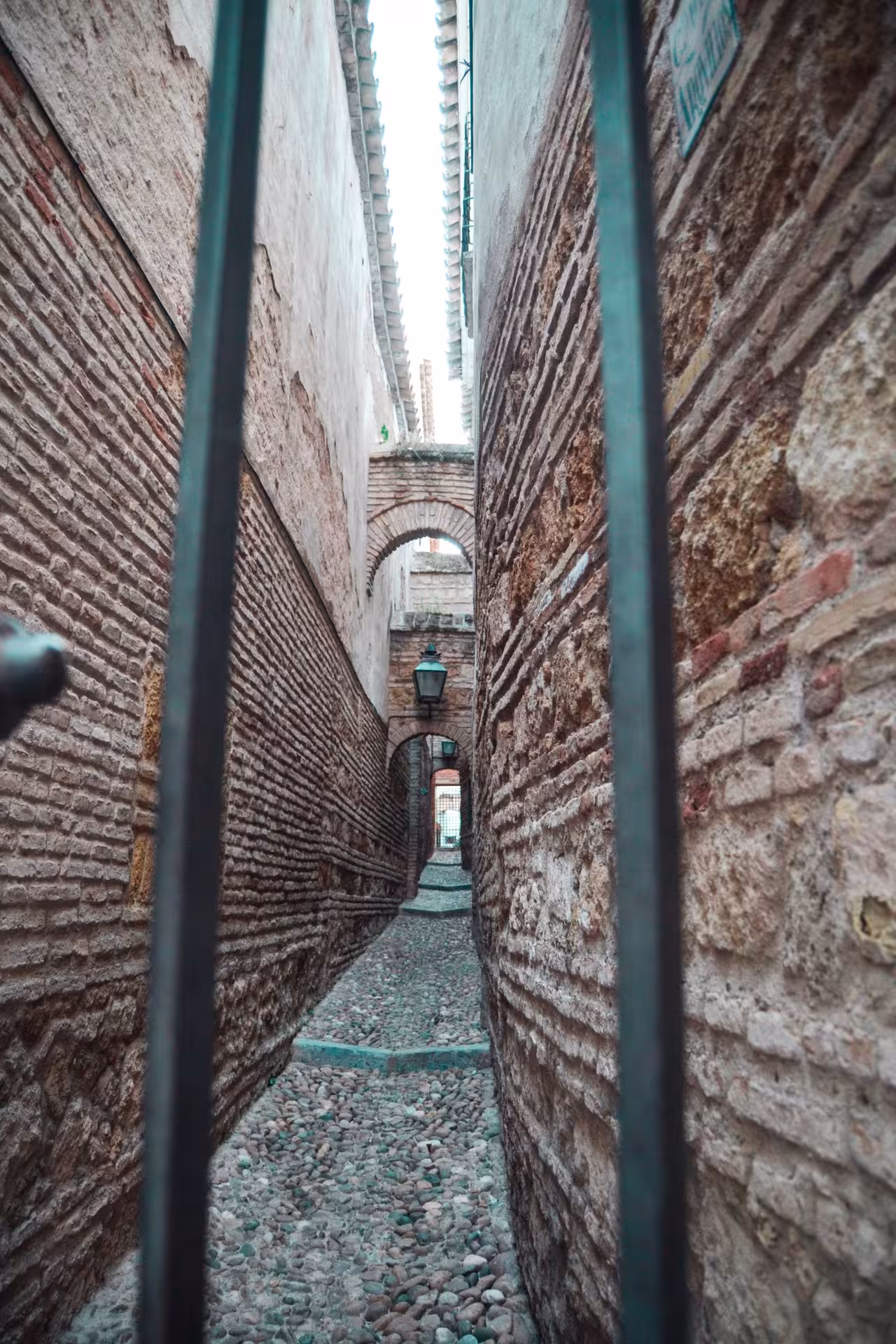Narrow cobblestone passageway in the Jewish Quarter showcasing ancient brick architecture and arches.