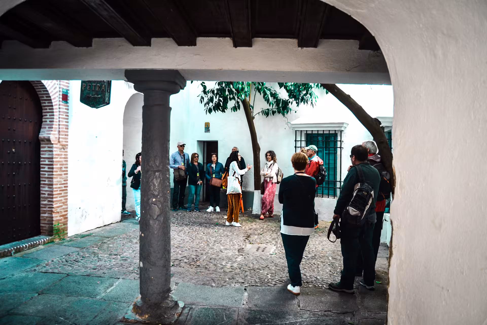 Group of tourists listening to a guide in a quaint courtyard during a tour of the Jewish Quarter.