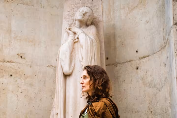 Woman standing before a medieval stone relief sculpture in Rouen during Joan of Arc walking tour