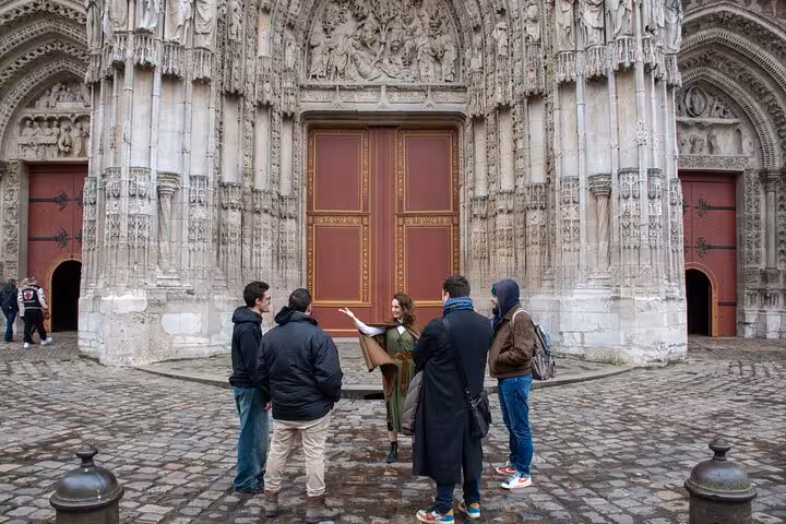 Tour guide leading a small group outside the ornate Gothic portal of Rouen Cathedral