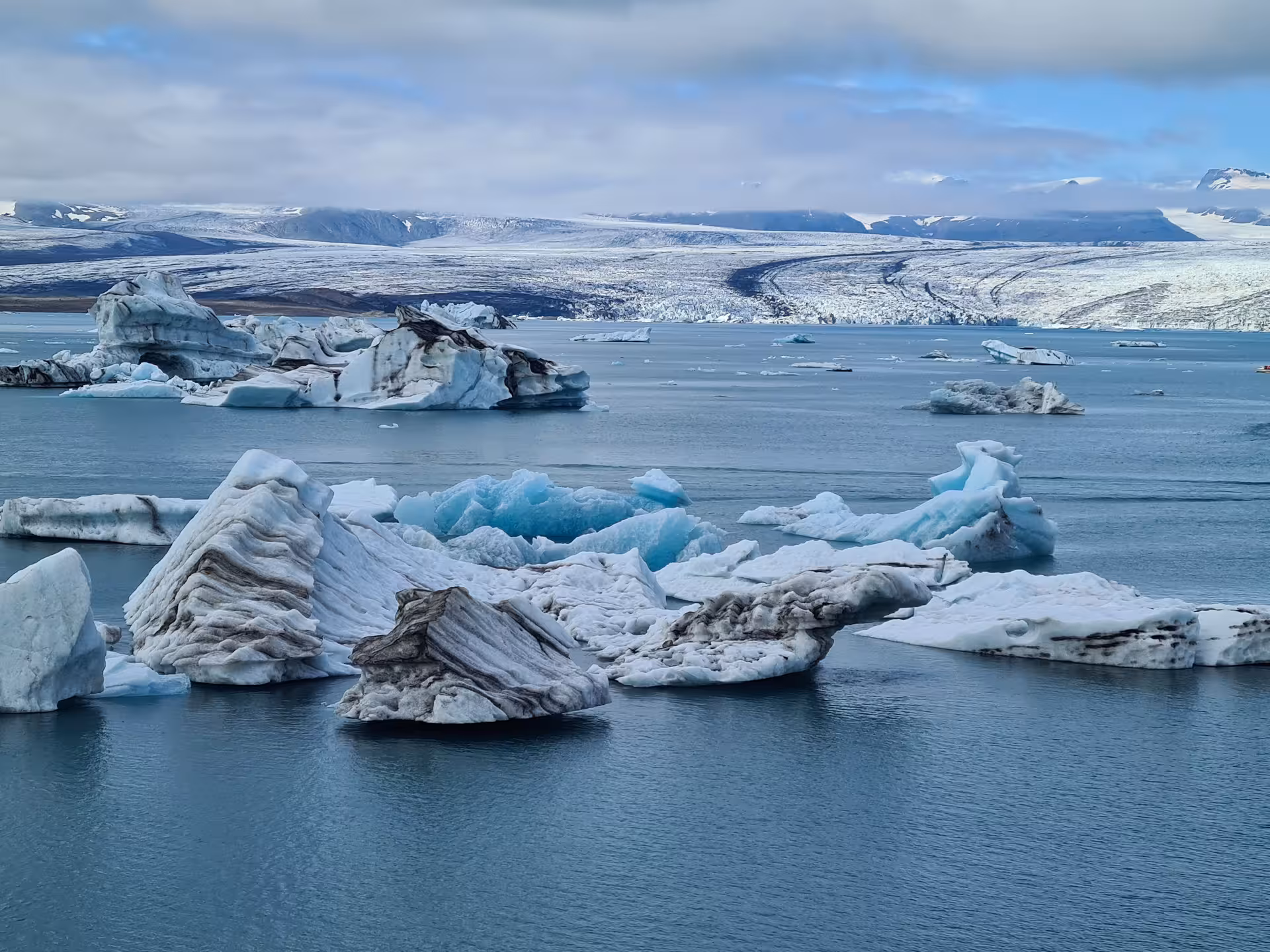 Icebergs floating on Jokulsarlon glacial lagoon with Vatnajokull glacier in background, Iceland