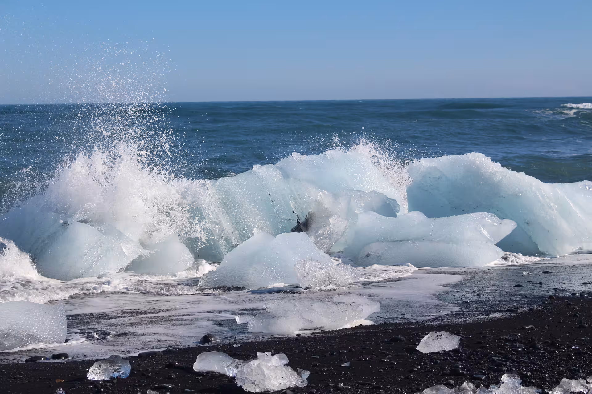 Glacial ice chunks on black sand beach with crashing Atlantic waves at Jokulsarlon, Iceland