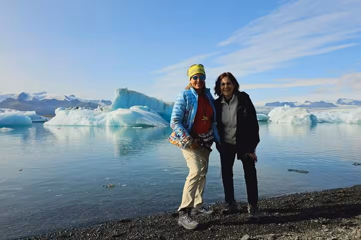 Two women posing together at Jokulsarlon Glacier Lagoon with floating icebergs in Iceland