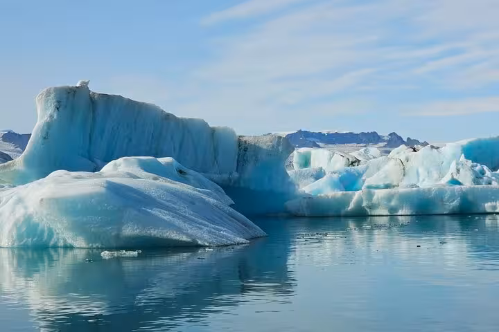 Large turquoise icebergs floating on calm glacial lagoon waters at Jokulsarlon, Iceland