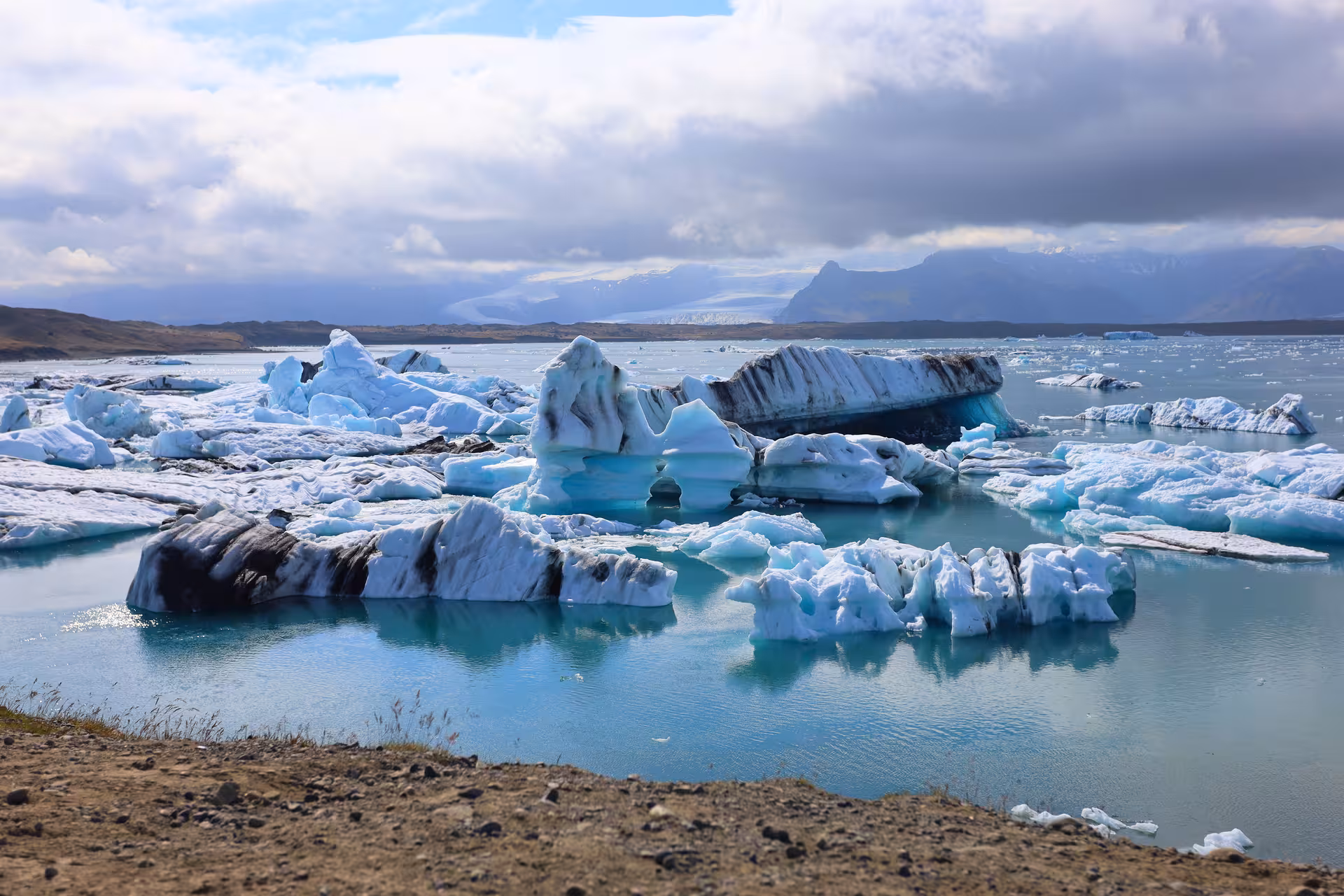 Floating icebergs with dark volcanic streaks on turquoise glacial lagoon at Jokulsarlon, Iceland