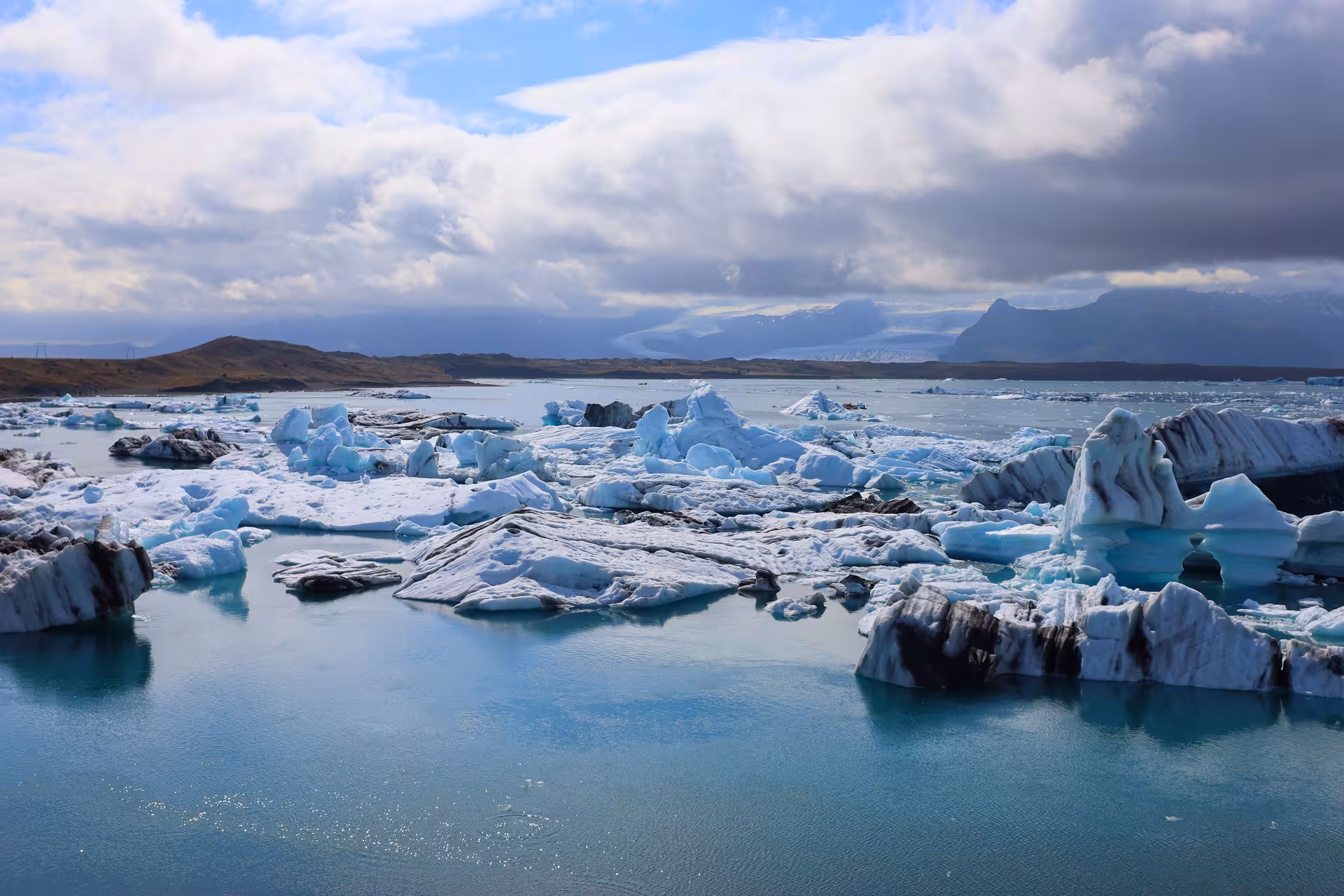 Icebergs floating in the turquoise waters of Jokulsarlon Glacier Lagoon with mountains in background