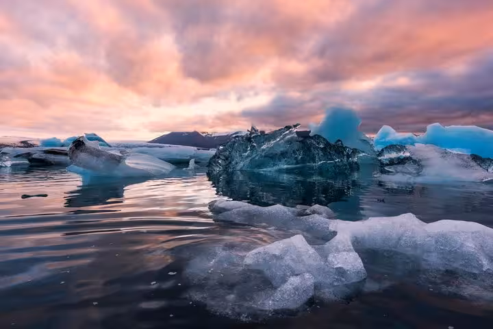 Icebergs floating in Jokulsarlon Glacier Lagoon at sunset with pink and purple sky