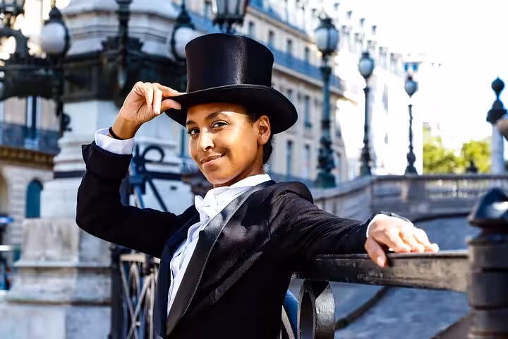 Woman in black tuxedo and top hat leaning on railing in Paris street