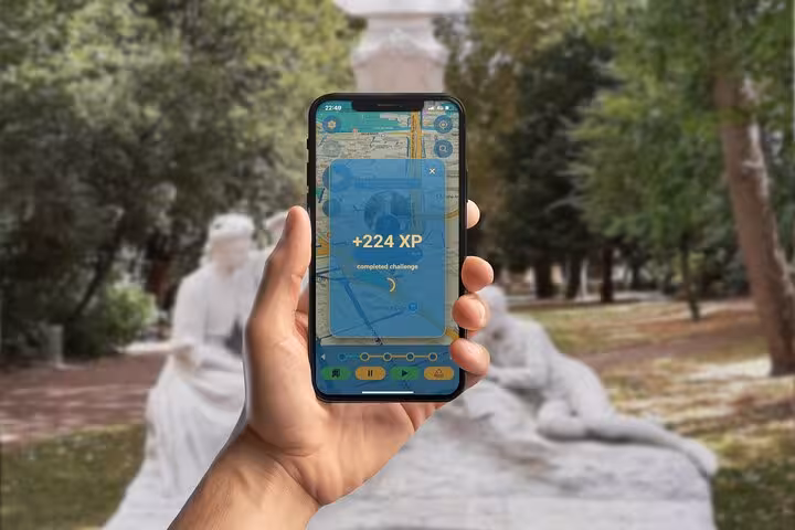 Hand holding smartphone showing +224 XP challenge completion on self-guided walking tour app near Amiens statue